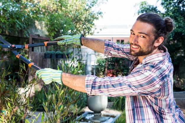 Ritratto del giardiniere felice che usando i tagliatori al giardino