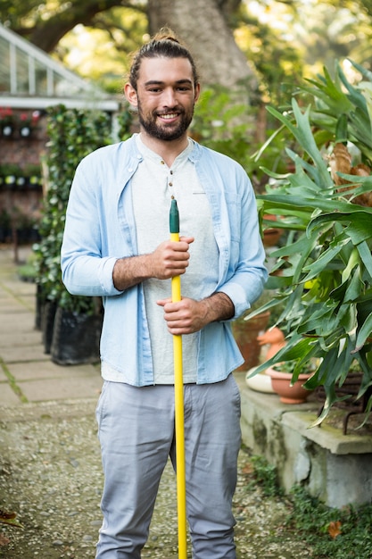 Ritratto del giardiniere felice con l'utensile manuale al giardino