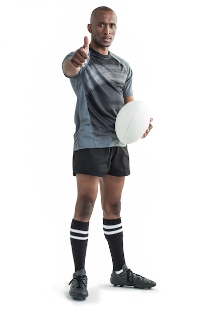 Ritratto del giocatore di rugby sicuro che mostra i pollici su mentre stando