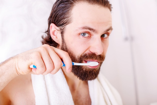 Ritratto del giovane che pulisce i suoi denti in bagno