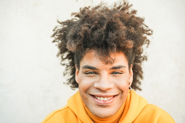 Ritratto del giovane della corsa mista - tipo afro felice che sorride davanti alla macchina fotografica - generazione millenaria e multi concetto di etnia - fuoco sul fronte