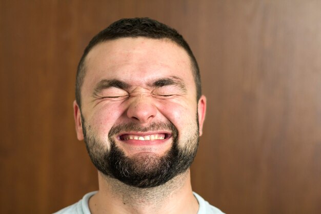 Ritratto del giovane moderno intelligente dai capelli neri bello barbuto in occhiali con taglio di capelli corto e occhi neri gentili sorridenti su sfondo sfocato. Concetto di gioventù e fiducia.