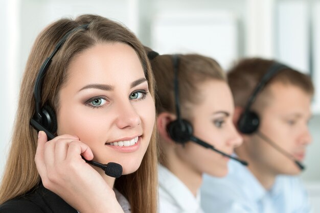 Ritratto del lavoratore del call center accompagnato dal suo team. Sorridente operatore del servizio clienti al lavoro. Aiuto e concetto di supporto