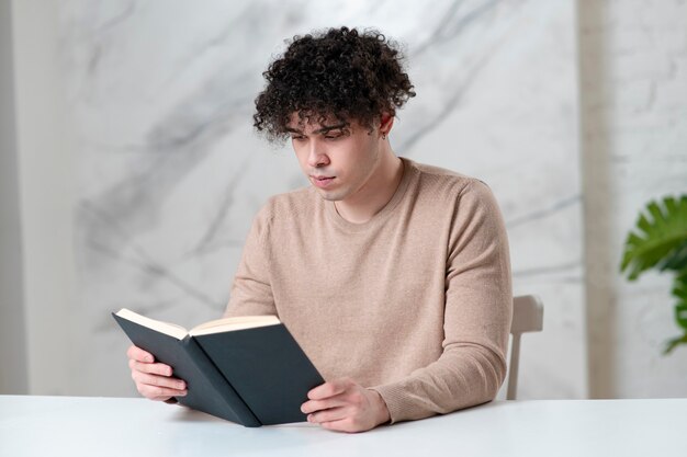 Ritratto del lettore di uomo intelligente concentrato giovane studente etnico bello ragazzo serio sta leggendo