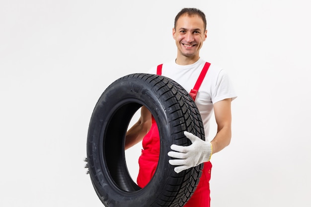 Ritratto del meccanico maschio sorridente che tiene pneumatico su sfondo bianco