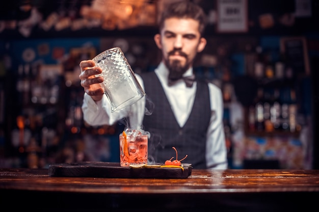 Ritratto del mixologist che versa la bevanda alcolica fresca nei bicchieri