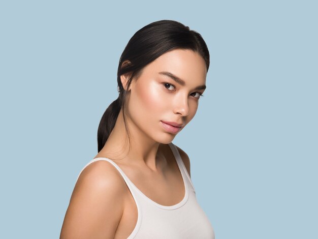 Ritratto del modello della pelle sana del viso della donna di bellezza dell'Asia. Colore di sfondo. Blu