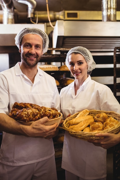 Ritratto del panettiere femminile e maschio che tiene canestro di pane e cibo dolce