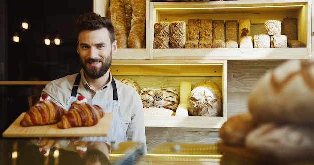 Ritratto del panettiere sorridente bello che lavora nel negozio del forno