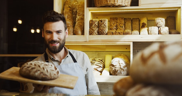 Ritratto del panettiere sorridente bello che lavora nel negozio del forno