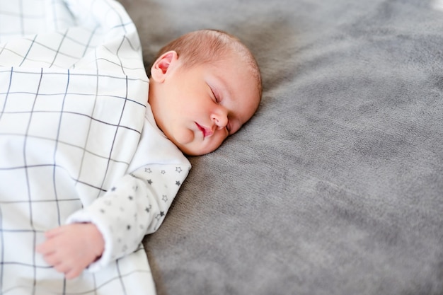 Ritratto del primo piano del neonato adorabile che dorme nel letto, concetto del bambino di 1 anno.