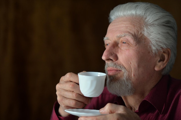 Ritratto del primo piano dell'uomo anziano che beve a casa