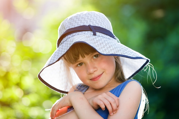 Ritratto del primo piano della bambina sorridente felice in un grande cappello.