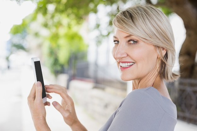 Ritratto del primo piano della donna che per mezzo dello smartphone