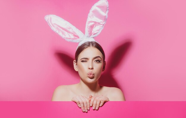 Ritratto del primo piano della ragazza allegra attraente che indossa il bacio dell'aria delle orecchie rosa Donna del coniglietto di Pasqua