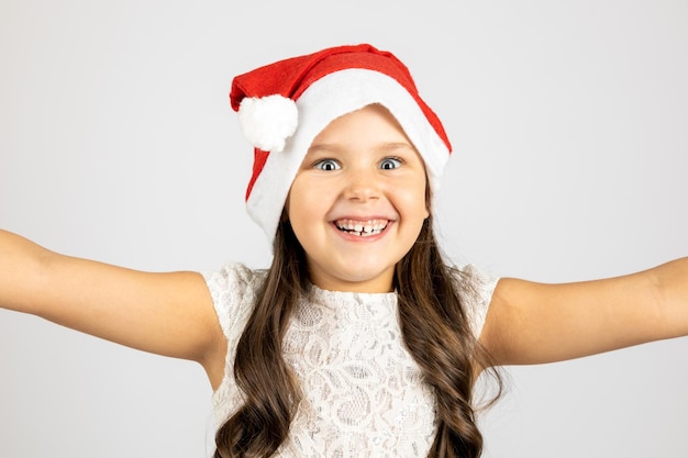 Ritratto del primo piano della ragazza di risata allegra in cappello di babbo natale che prende selfie isolato su un backg bianco...