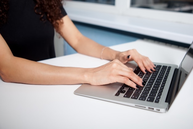 Ritratto del primo piano delle mani della donna che digitano sulla tastiera del computer