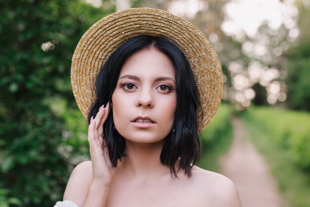 Ritratto del primo piano di bella donna sensuale in cappello di paglia.