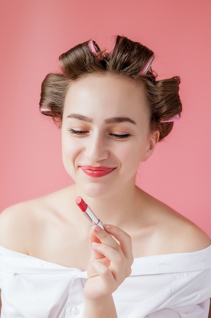 Ritratto del primo piano di bella ragazza che mette sul rossetto rosso.