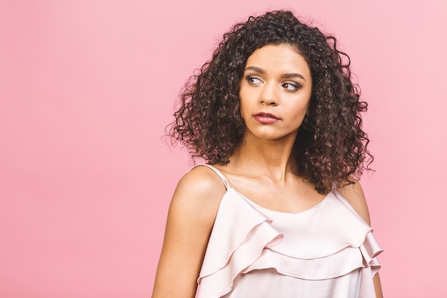 Ritratto del primo piano di bellezza di giovane ragazza afroamericana con afro. Ragazza isolata su sfondo rosa. Pelle ideale.