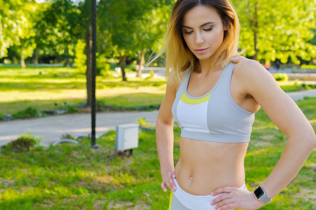 Ritratto del primo piano di giovane bella donna di sport nel parco di estate