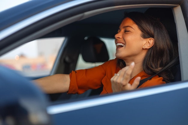 Ritratto del primo piano di lei lei bella attraente bella bruna affascinante felice allegra ragazza allegra guidando una nuova auto godendosi divertendosi ascoltando musica cantando pop rock