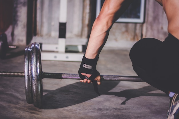 Ritratto del primo piano di un allenamento muscolare dell&#39;uomo con il bilanciere alla palestra locale