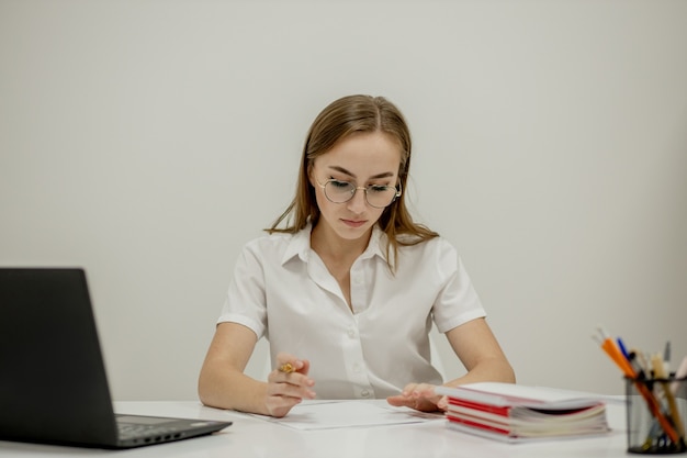 Ritratto del primo piano di un giovane responsabile dell'ufficio femminile sicuro al suo posto di lavoro, pronto per fare attività di affari