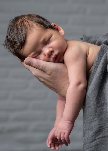 Ritratto del primo piano di un neonato che si trova sulla grande mano di un papà premuroso