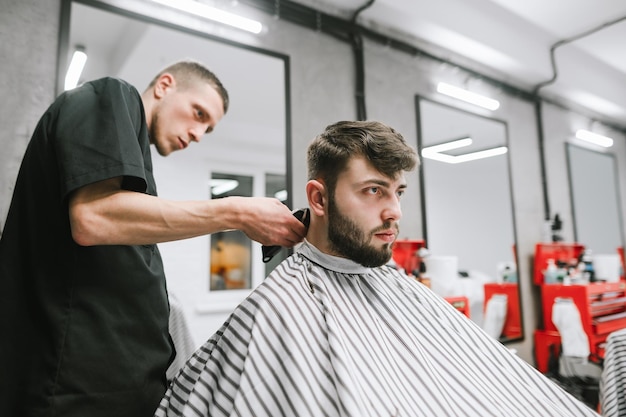 Ritratto del primo piano di un uomo barbuto che taglia un barbiere da un parrucchiere da uomo