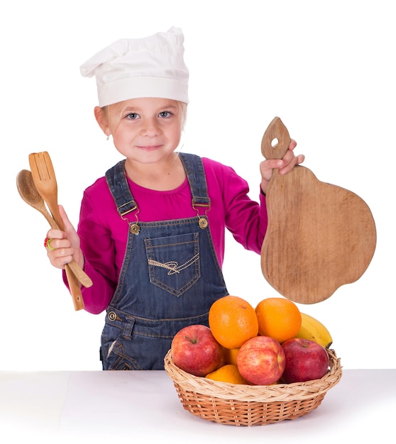 Ritratto del primo piano di una bambina che tiene frutta mele banane e arance ed elettrodomestici da cucina isolati su uno sfondo chiaro