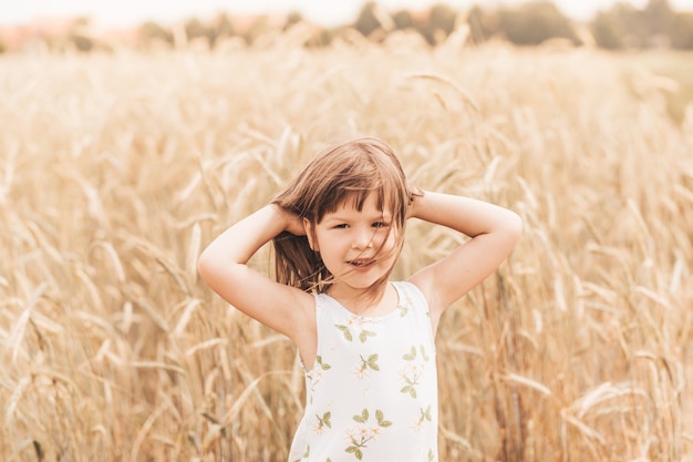 Ritratto del primo piano di una bionda sorridente della bambina in natura in estate