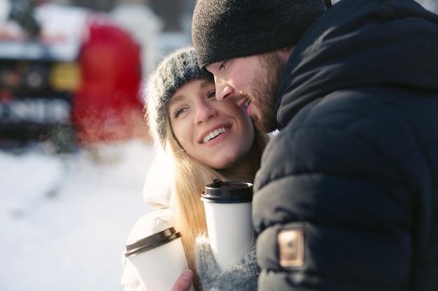 Ritratto del primo piano di una coppia felice Uomini e donne che abbracciano e che ridono in un parco di neve d'inverno