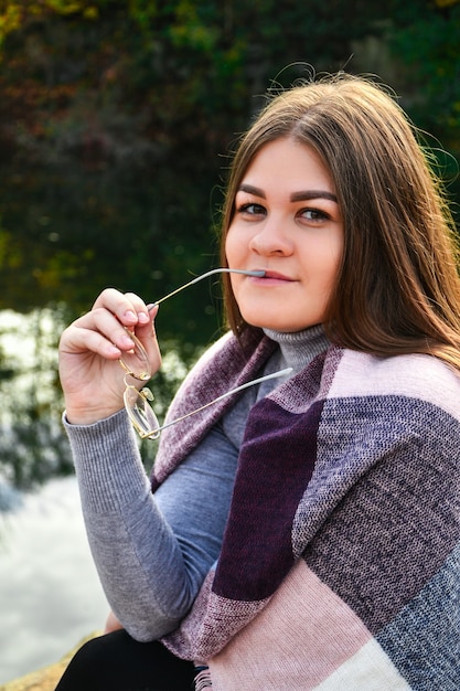 Ritratto del primo piano di una donna con sciarpa sul lago. Fuori da. Ragazza sorridente felice. Amante della natura