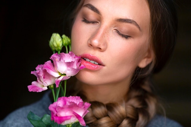 Ritratto del primo piano di una donna con un fiore con gli occhi chiusi