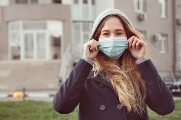 Ritratto del primo piano di una donna in una mascherina medica sulla via, epidemia di un coronavirus. la donna ha violato le regole di autoisolamento. SARS-CoV-2. proteggiti da COVID-19.