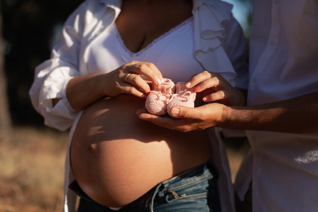 Ritratto del primo piano di una donna incinta e di suo marito che tengono un paio di stivaletti per bambini all'uncinetto