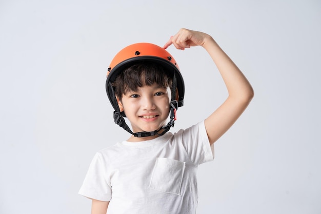 ritratto del ragazzo asiatico che indossa il casco arancione su sfondo bianco