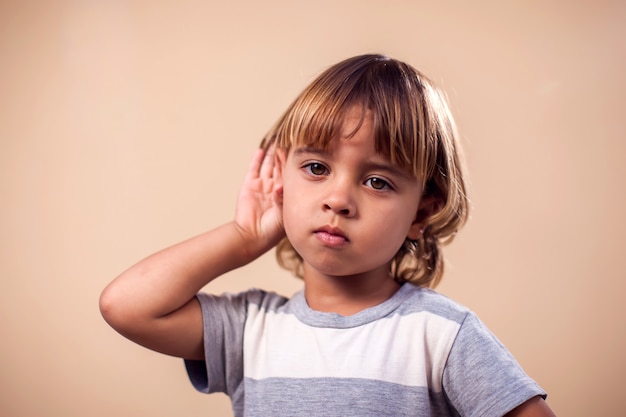 ritratto del ragazzo del bambino che ascolta di nascosto una conversazione. Concetto di bambini ed emozioni