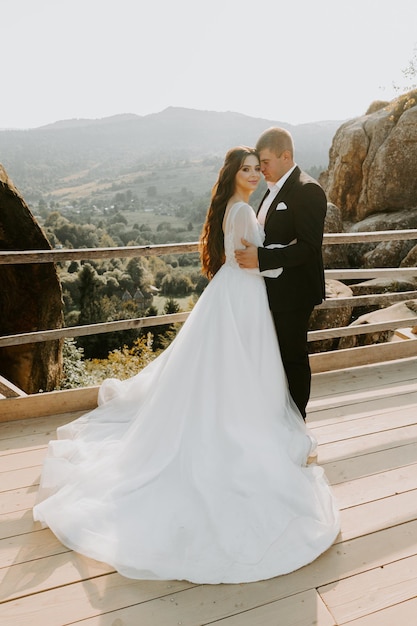 Ritratto del sole della sposa e dello sposo felici all'aperto nella posizione della natura al tramonto. Estate calda