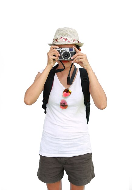 Ritratto del viaggiatore della ragazza che prende foto con la macchina fotografica isolata su fondo bianco