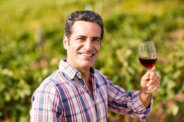 Ritratto del vignaiolo maschio sorridente che tiene un bicchiere di vino