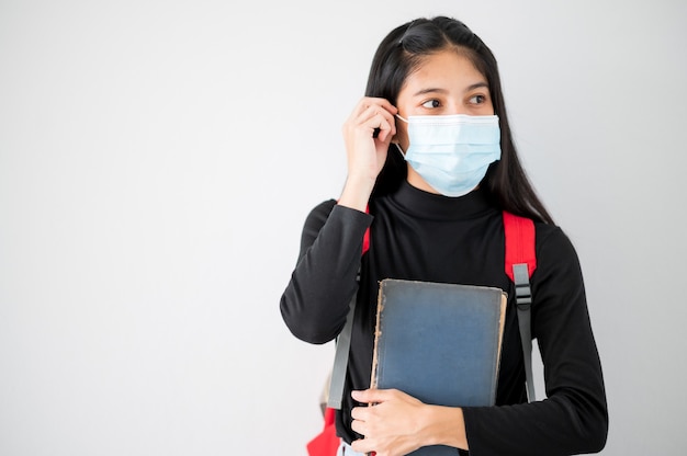 Ritratto del viso del primo piano Studenti asiatici universitari femminili indossano una maschera e mantengono le distanze sociali durante l'orario scolastico.