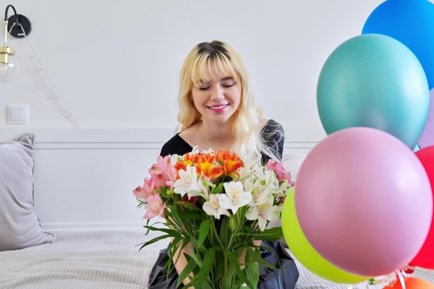 Ritratto dell'adolescente della ragazza di compleanno con il mazzo dei fiori e degli aerostati a casa