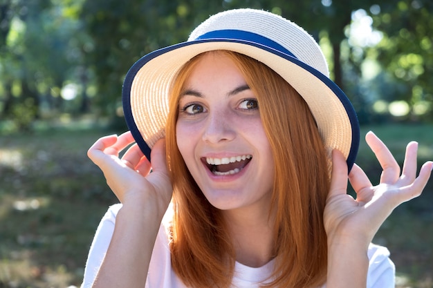 Ritratto dell'adolescente sorridente splendido in cappello giallo e con capelli rossi all'aperto il giorno di estate soleggiato.