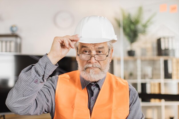 Ritratto dell'architetto maturo che indossa il casco bianco della costruzione all'interno