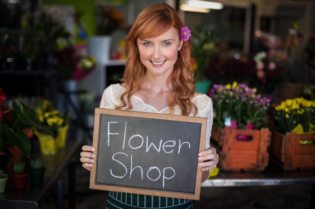 Ritratto dell'ardesia femminile della tenuta del fiorista con il segno del negozio di fiore