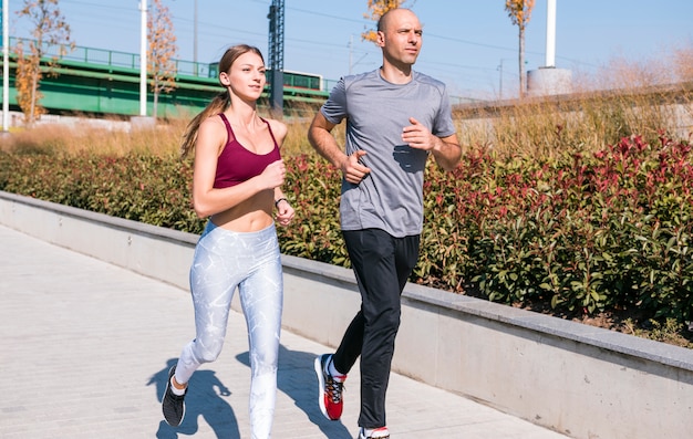 Ritratto dell&#39;atleta femminile e maschio che corre insieme nel parco