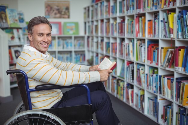 Ritratto dell'insegnante di scuola disabile che tiene il libro in biblioteca