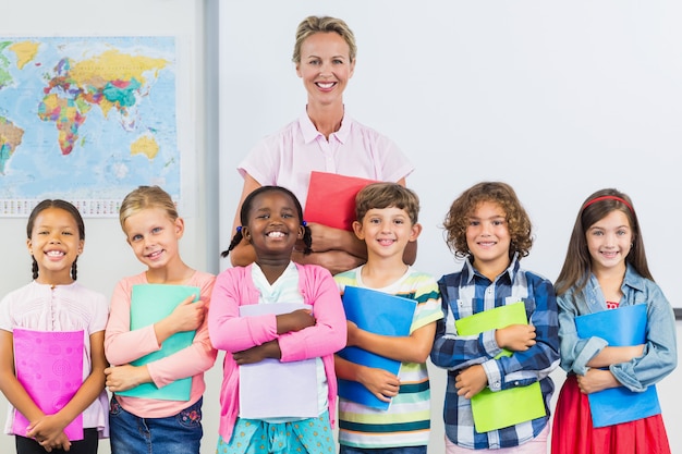 Ritratto dell'insegnante e dei bambini sorridenti che stanno nell'aula